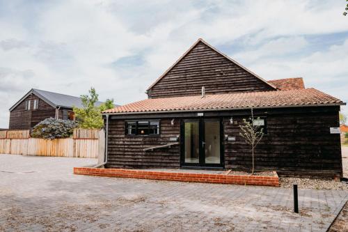 uma pequena casa com telhado castanho em Creeksea Place Barns em Burnham on Crouch