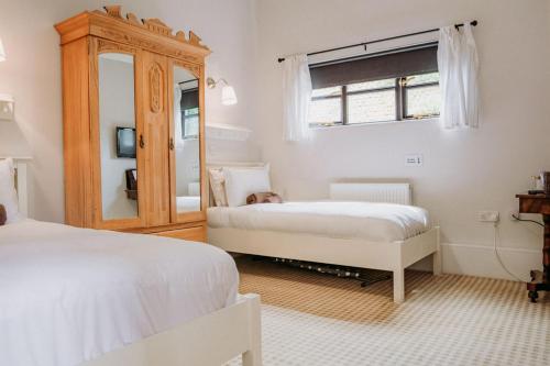 1 dormitorio con 2 camas y espejo en Creeksea Place Barns en Burnham on Crouch
