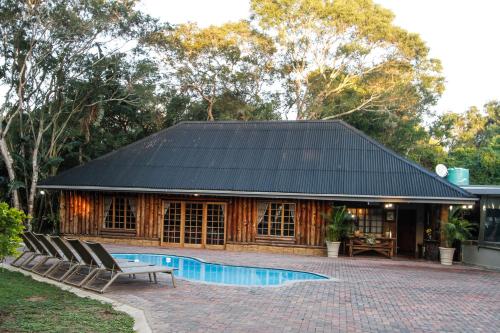 a house with a black roof and a swimming pool at Ezulwini Game Lodge in Hluhluwe