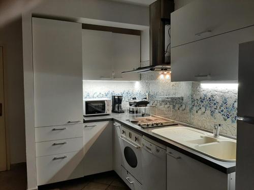 a kitchen with white cabinets and a sink at Cosy, sea view apartment Porat in Porat