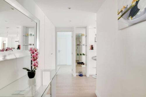 un couloir blanc avec un miroir et un vase de fleurs dans l'établissement C066-Luxurious apartment with sea view - Cannes, à Cannes