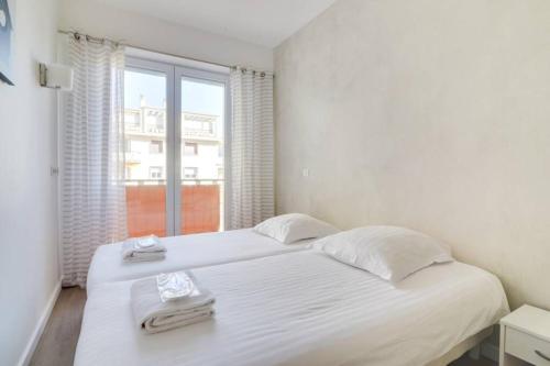 une chambre blanche avec un grand lit et une fenêtre dans l'établissement C066-Luxurious apartment with sea view - Cannes, à Cannes
