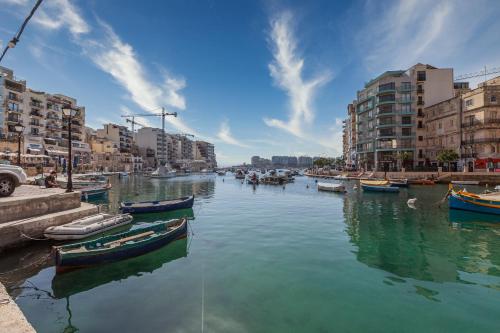 a group of boats in a river with buildings at The G Hotel by JL in St Julian's