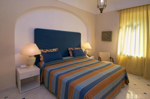 a bedroom with a large bed with a blue headboard at Grand Hotel Aminta in Sorrento