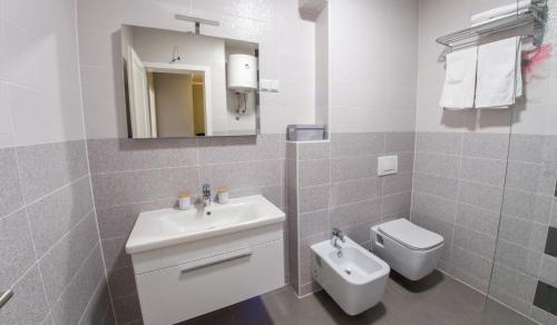 a white bathroom with a sink and a toilet at Apartment Light De Luxe - with Old Bridge view in Mostar