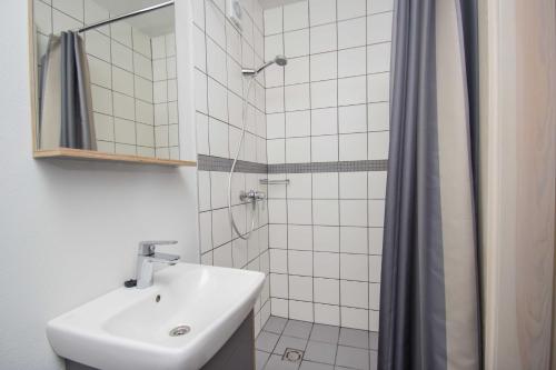La salle de bains blanche est pourvue d'un lavabo et d'une douche. dans l'établissement FORUS apartments in Sventoji, à Šventoji