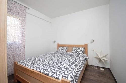 Schlafzimmer mit einem Bett mit einer schwarzen und weißen Bettdecke in der Unterkunft Apartments Nina Tivat in Tivat