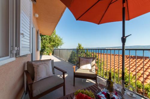 a balcony with an umbrella and a table and chairs at Apartment Lea in Stanići