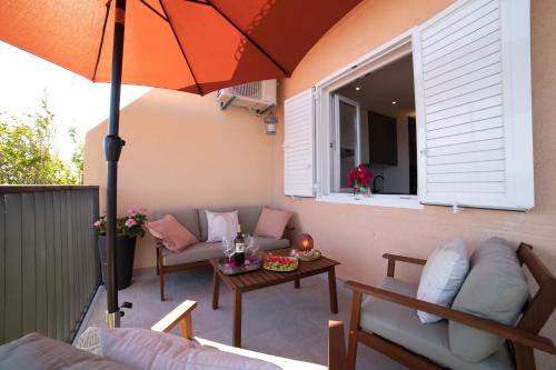 a patio with an umbrella and couches and a table at Apartment Lea in Stanići