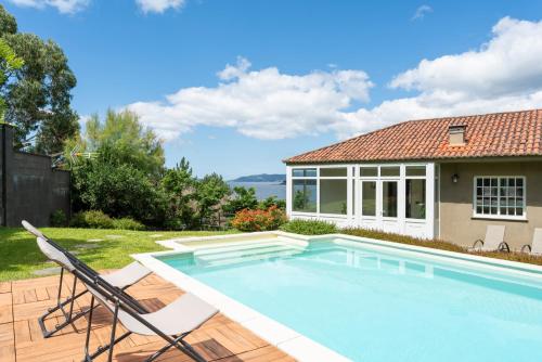 una piscina con dos sillas y una casa en Casa Boa, en Porto do Son