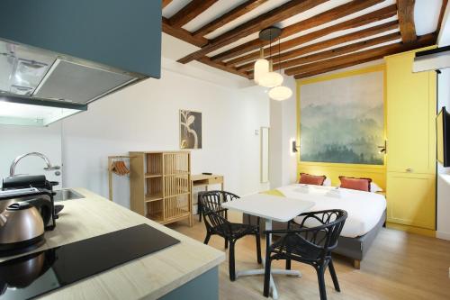 - une cuisine avec une table et un lit dans une chambre dans l'établissement Rent a Room - Aparts CADET, à Paris