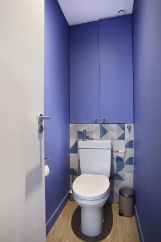 La salle de bains est pourvue de toilettes et de murs bleus. dans l'établissement Rent a Room - Aparts CADET, à Paris