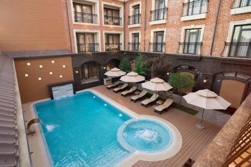 an outdoor swimming pool with umbrellas and tables and a building at OSCAR BOUTIQUE HOTEL in Tashkent