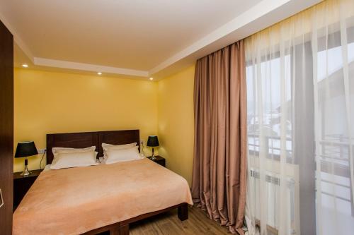 1 dormitorio con cama y ventana grande en Crystal Hill Resort, en Bakuriani
