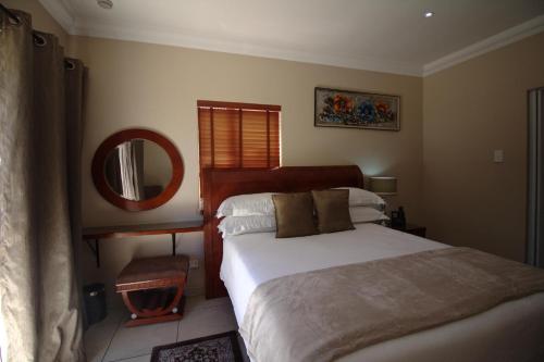 a bedroom with a large bed and a mirror at Lakeview Boutique Hotel & Conference Center in Benoni
