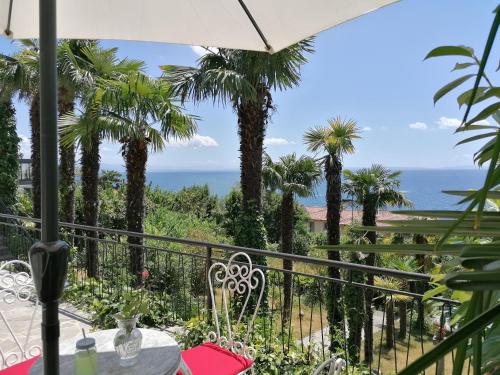 een balkon met palmbomen en uitzicht op de oceaan bij K&M Apartment in Opatija