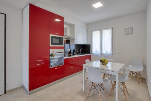 a kitchen with red cabinets and a white table and chairs at La Sensa Apartments in Brenzone sul Garda
