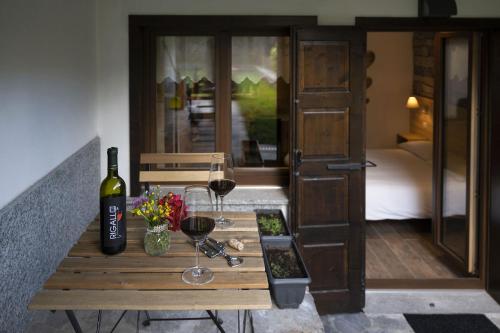 a wooden table with two glasses of wine and flowers at Casa Galèt in Tirano