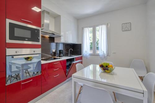 a kitchen with red cabinets and a white table at La Sensa Apartments in Brenzone sul Garda