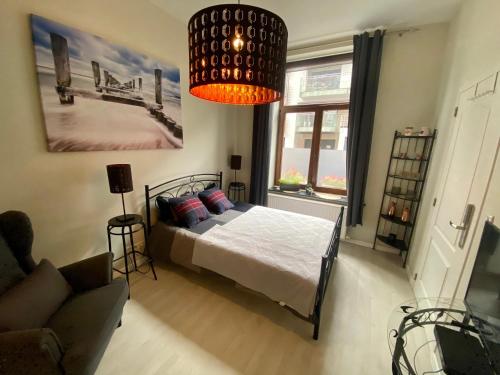 ブリュッセルにあるPetit Appartement Jourdan EUのベッドルーム1室(ベッド1台、シャンデリア付)