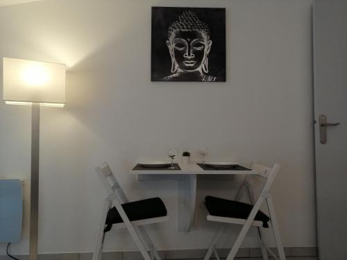 une table et des chaises avec une photo d'une tête sur le mur dans l'établissement Apt T1 Cosy et ambiance Zen 