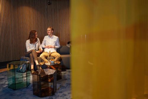 two people sitting on a couch in a room at The Florian Amsterdam Schiphol Airport, WorldHotels Crafted in Hoofddorp