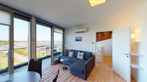 un soggiorno con divano blu e vetrate a tutta altezza di Speicher Residenz Barth E5 App 6 a Barth