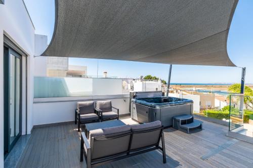 a patio with a grill and chairs on a balcony at Villa Miragem Alvor in Alvor