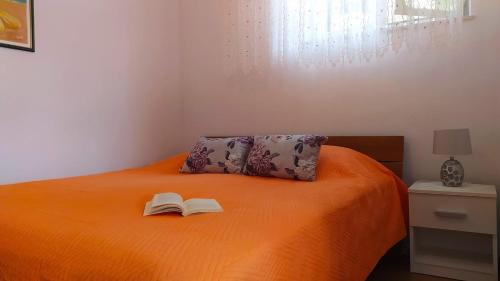 a bed with an open book with a book at Garden apartment with a View in Postira