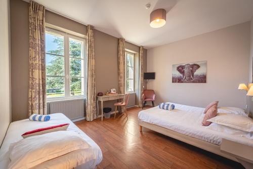 sypialnia z 2 łóżkami, biurkiem i oknami w obiekcie Domaine de Roiffé w mieście Roiffé