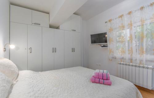 een witte slaapkamer met een roze kussen op een bed bij Apartmani Cupar in Poreč
