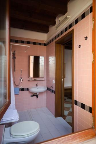 a pink bathroom with a toilet and a sink at Cornarorooms in Castelfranco Veneto