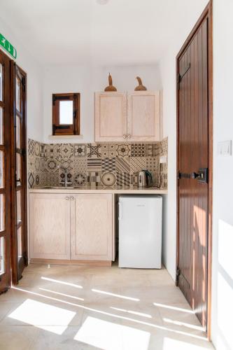 a kitchen with white cabinets and a white refrigerator at Droshia Traditional Homes, COCO-MAT Full Experience in Drousha