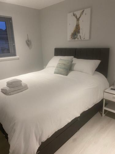 a bedroom with a bed with white sheets and a window at Number Fifty Six in Saint Monance