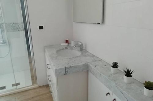 a white bathroom with a sink and a shower at Nuvoleinviaggio in Sulmona