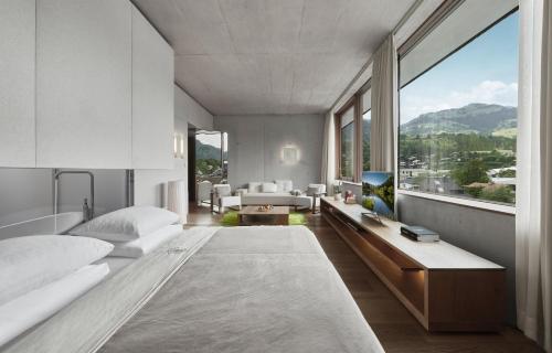 a bedroom with two beds and a large window at Schwarzer Adler Kitzbühel - Adults Only in Kitzbühel
