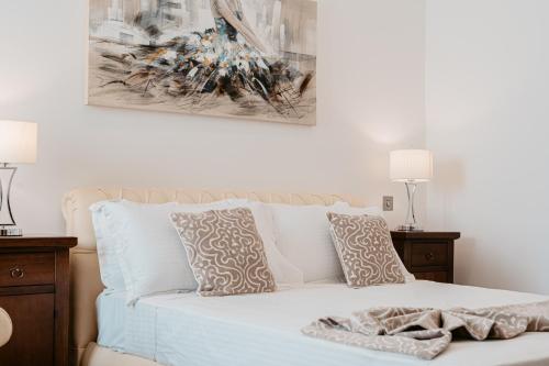 a white bed with two pillows and a painting on the wall at Palazzo Violetta in Sliema