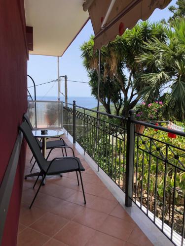a balcony with a table and a chair and the ocean at Elena Rista Studios in Parga