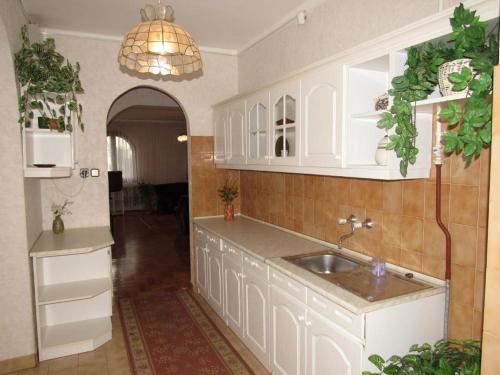 una cocina con armarios blancos y fregadero en Kossuth Apartman, en Hajdúszoboszló