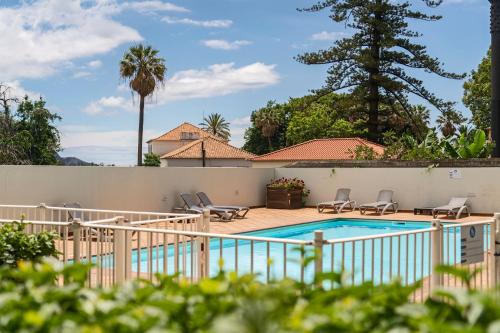 a swimming pool in a yard with chairs and a fence at Jasmineiro II by An Island Apart in Funchal