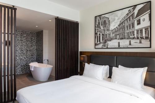 a bedroom with a bed and a bath tub and a sink at Radisson Hotel & Suites Amsterdam South in Amstelveen