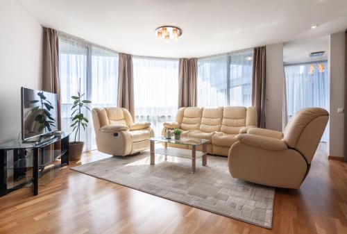 a living room with a couch and chairs and a tv at Elija Swan-Toy Apartments in Šventoji