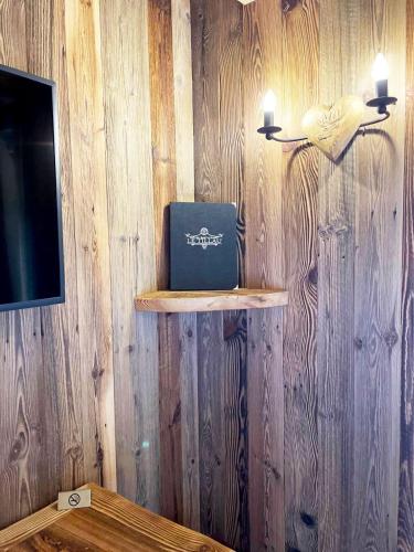 a room with a wooden wall with a laptop on a shelf at Le Tillau in Les Verrières-de-Joux