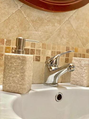 a bathroom sink with a faucet and a soap dispenser at Suite Arco 166 Stanza privata in Trani