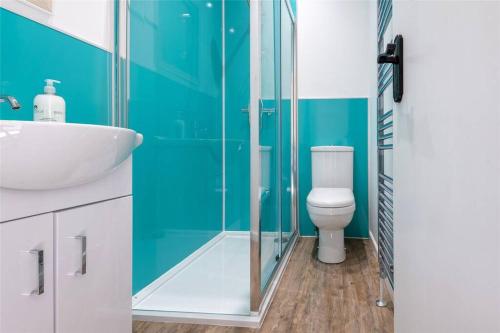 a bathroom with a toilet and a glass shower at The Colours Riverside apartment with garden in Broughty Ferry