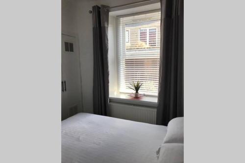 a bedroom with a bed and a window at The Colours Riverside apartment with garden in Broughty Ferry