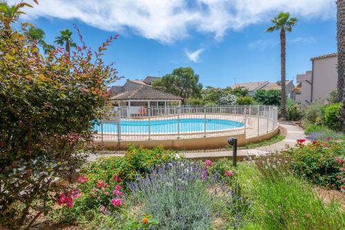 - une piscine dans un jardin fleuri dans l'établissement Residence Residhotel Mayflower, au Grau-du-Roi