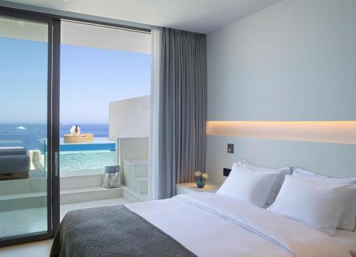 a bedroom with a bed and a view of the ocean at White Coast Pool Suites, Adults Only - Small Luxury Hotels of the World in Mytakas