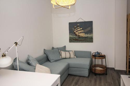 a living room with a blue couch and a painting of a ship at Casa Kant in SantʼAntìoco