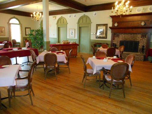 a dining room with tables and chairs and a fireplace at Braeside Country Inn in Pictou